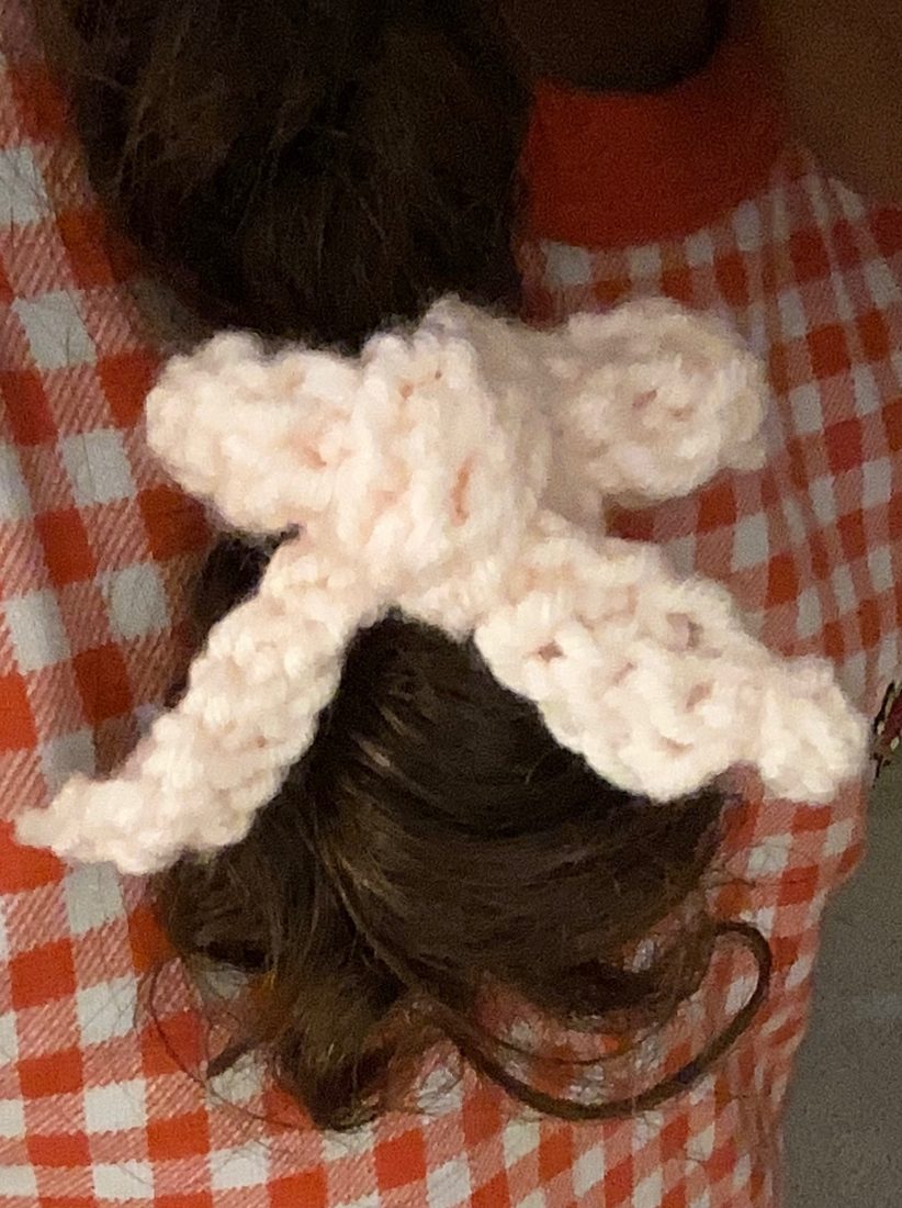 Blush crochet bow worn in dark curly hair