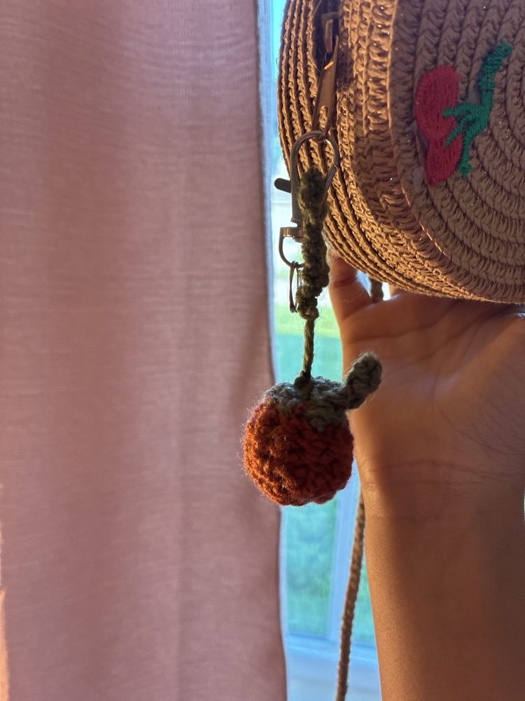 Peachy-orange crochet fruit charm with a green leaf